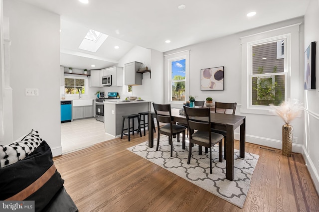 dining room featuring baseboards, a wealth of natural light, and light wood-type flooring