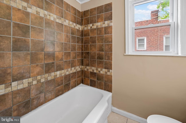 full bath featuring baseboards, tile patterned flooring, toilet, and a bathing tub