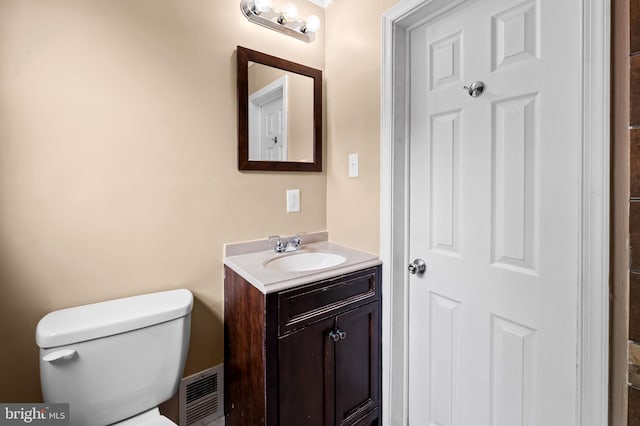 bathroom with toilet, visible vents, and vanity