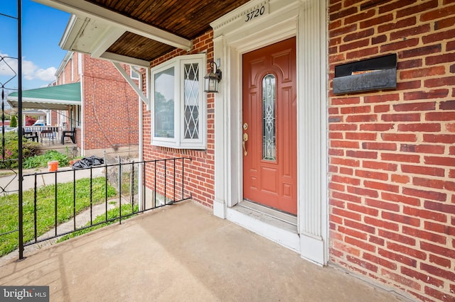 property entrance featuring a porch and brick siding