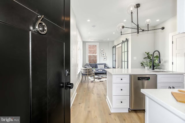 kitchen with light wood finished floors, light countertops, dishwasher, a sink, and white cabinetry