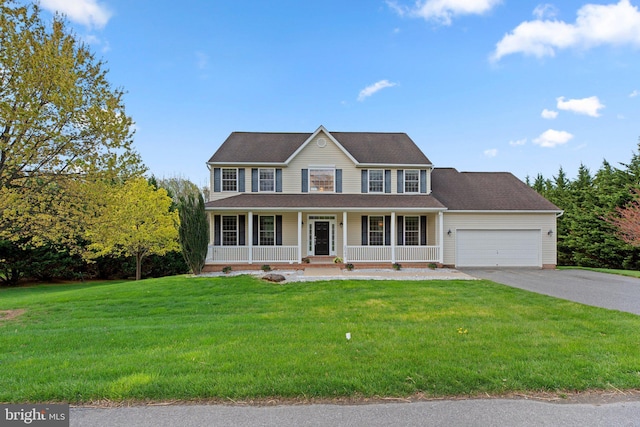 colonial house featuring a porch, an attached garage, a front lawn, and aphalt driveway