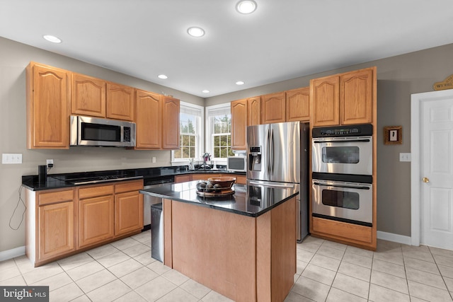 kitchen with a center island, baseboards, appliances with stainless steel finishes, and light tile patterned floors
