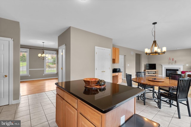 kitchen with dark countertops, open floor plan, an inviting chandelier, light brown cabinets, and light tile patterned floors
