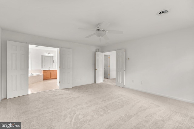 unfurnished bedroom with light carpet, ensuite bath, visible vents, and baseboards