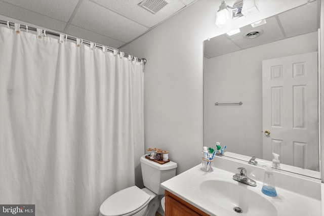 bathroom with toilet, visible vents, vanity, and a drop ceiling