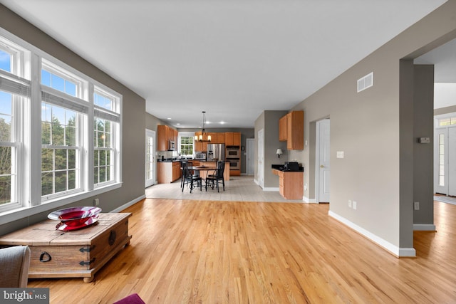 living room featuring baseboards, an inviting chandelier, visible vents, and light wood-style flooring