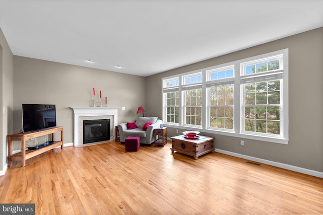 living room featuring wood finished floors, visible vents, baseboards, and a healthy amount of sunlight
