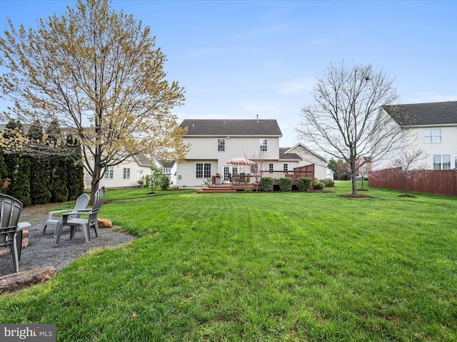 rear view of house with a lawn, fence, and a deck