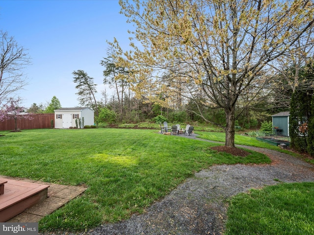 view of yard with a storage unit, a fire pit, fence, and an outbuilding