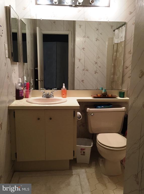 bathroom with toilet, vanity, tile patterned floors, and wallpapered walls