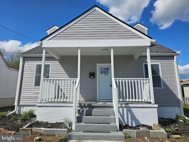 bungalow-style house featuring a porch, a chimney, and a shingled roof