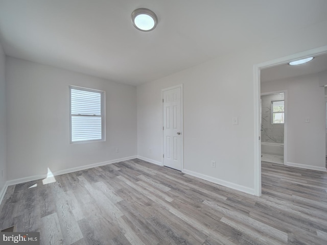 spare room with baseboards and wood finished floors