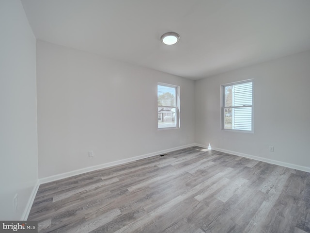 spare room with baseboards and wood finished floors