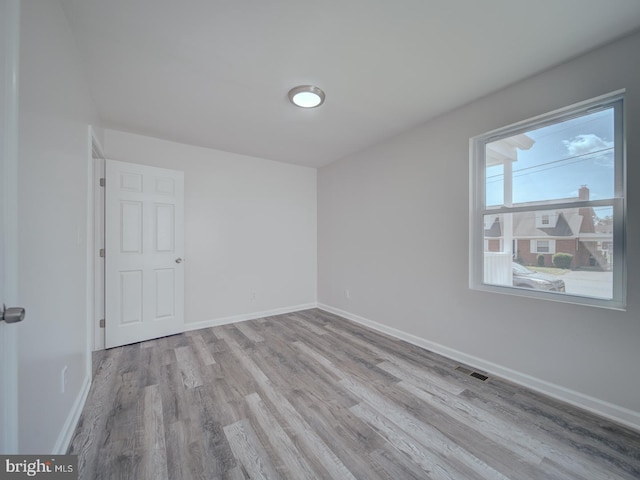 spare room featuring wood finished floors, visible vents, and baseboards