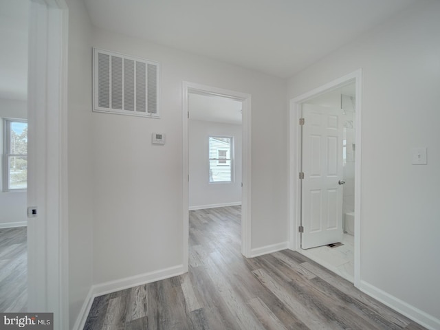 corridor with wood finished floors, visible vents, and baseboards