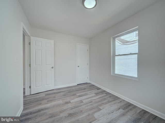 unfurnished bedroom with baseboards and light wood-style flooring
