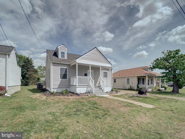 view of front facade featuring central AC, a front yard, a shingled roof, and covered porch