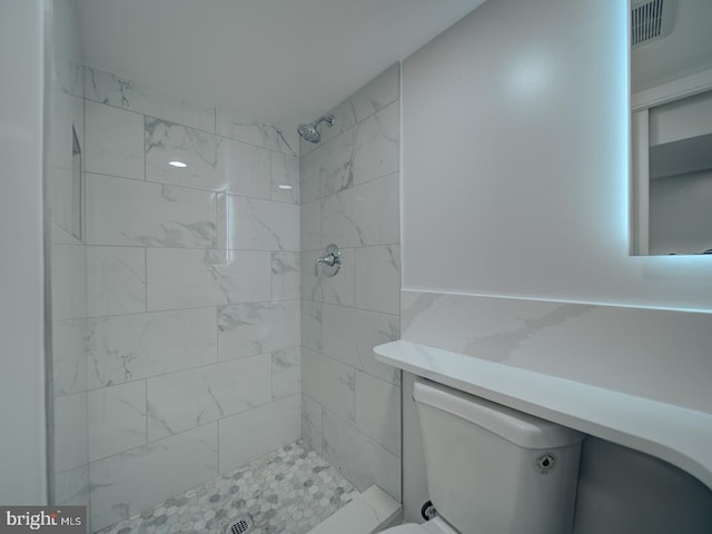 bathroom featuring a tile shower, visible vents, and toilet