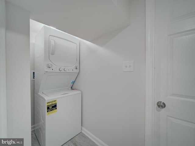 laundry room featuring baseboards, stacked washer / dryer, and laundry area