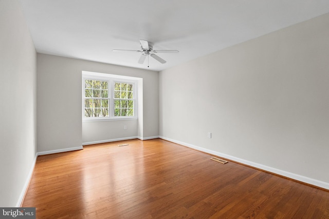 empty room featuring visible vents, ceiling fan, wood finished floors, and baseboards