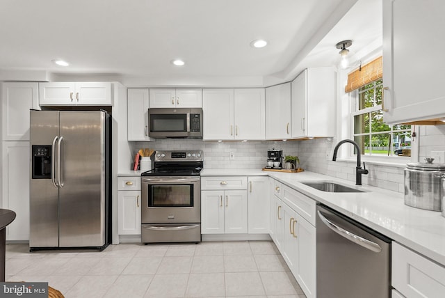 kitchen featuring a sink, decorative backsplash, stainless steel appliances, light countertops, and white cabinets