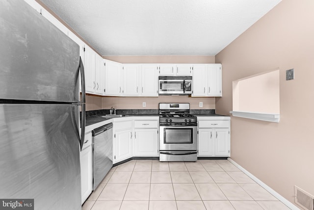 21 Fisher Dr, Franklin Park, NJ 08823 - kitchen with stainless steel appliances, dark countertops, white cabinets, light tile patterned floors, and a sink