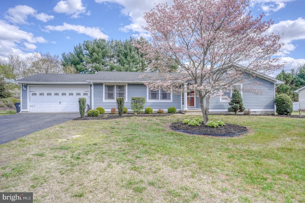 ranch-style home featuring an attached garage, driveway, and a front lawn