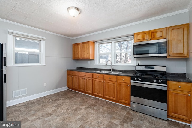 kitchen featuring dark countertops, a sink, brown cabinets, stainless steel appliances, and visible vents