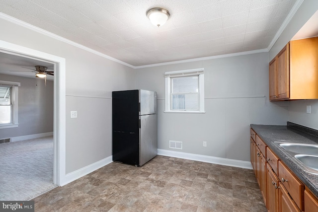 kitchen with dark countertops, visible vents, freestanding refrigerator, brown cabinets, and crown molding