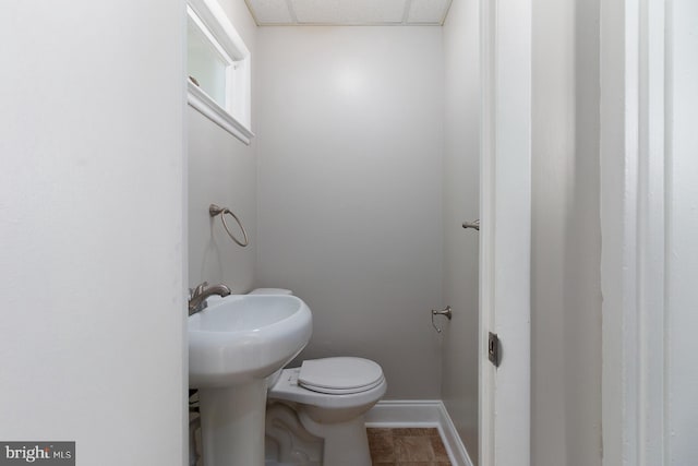 bathroom with tile patterned flooring, toilet, baseboards, and a drop ceiling
