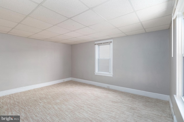 carpeted empty room with baseboards and a paneled ceiling