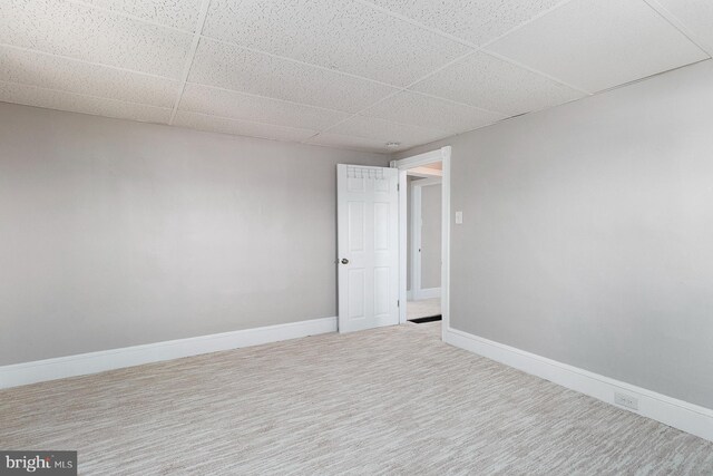 carpeted empty room with a drop ceiling and baseboards