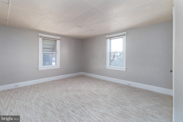 unfurnished room featuring carpet flooring, a drop ceiling, and baseboards