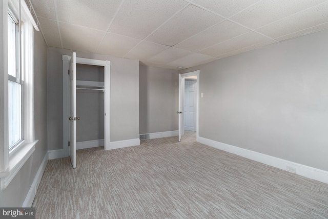 unfurnished bedroom with a paneled ceiling, baseboards, a closet, and carpet flooring