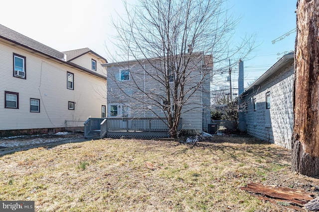 back of property featuring a wooden deck and a lawn