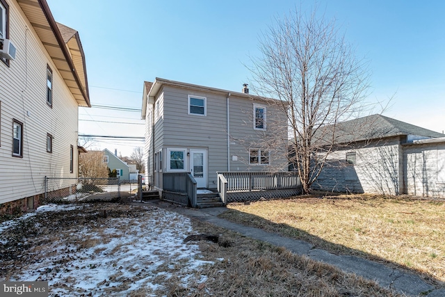 snow covered property with fence, a wooden deck, a lawn, and a chimney