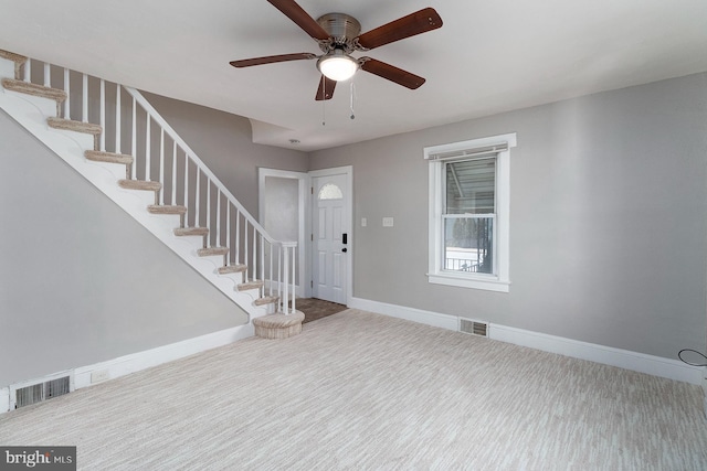 carpeted foyer entrance with baseboards, visible vents, and stairway