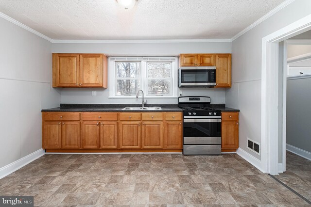 kitchen with dark countertops, a sink, brown cabinets, stainless steel appliances, and visible vents