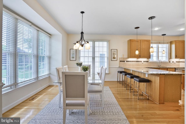 dining area featuring a chandelier, light wood-style flooring, baseboards, and recessed lighting