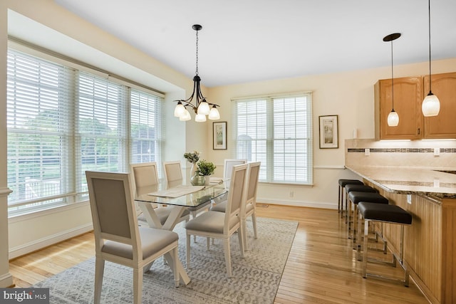 dining space featuring a chandelier, baseboards, and light wood-type flooring