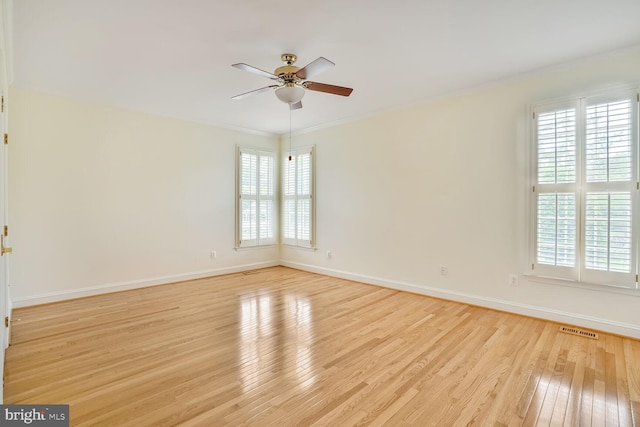 unfurnished room featuring hardwood / wood-style flooring, ceiling fan, baseboards, and crown molding