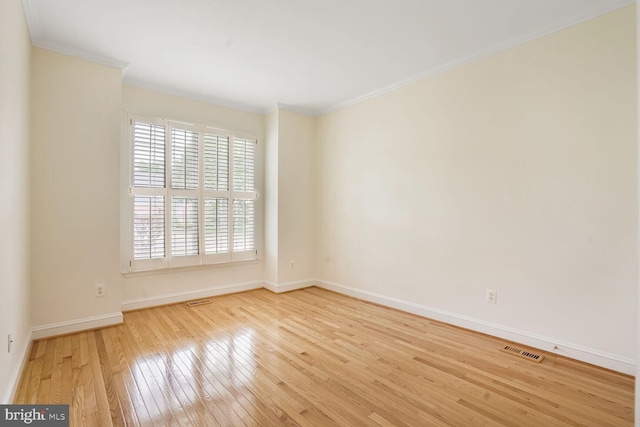 spare room with crown molding, hardwood / wood-style floors, and baseboards