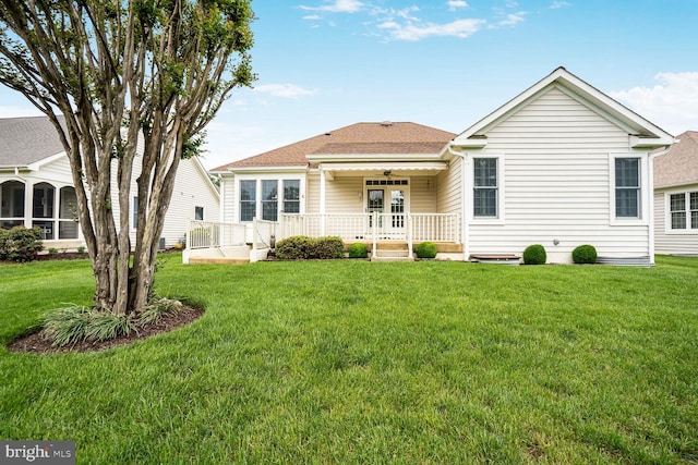 rear view of property with ceiling fan, a lawn, and a shingled roof