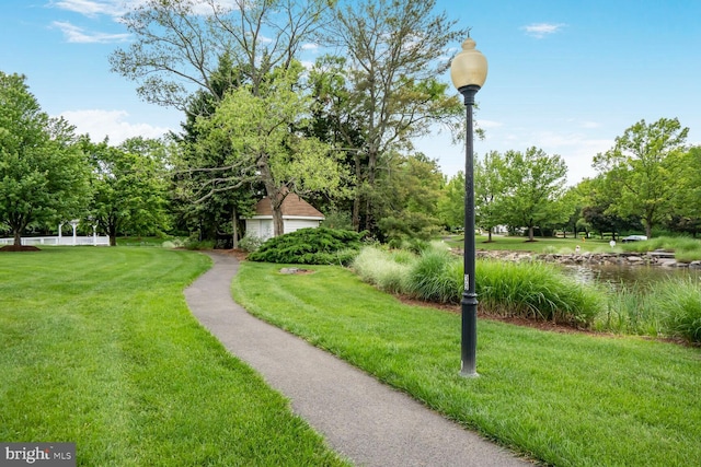 surrounding community featuring a lawn and view of wooded area