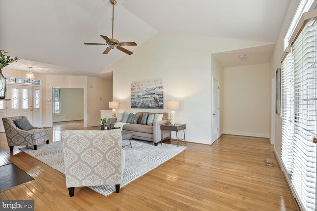 living area with high vaulted ceiling, light wood-style floors, a ceiling fan, and baseboards