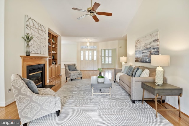 living area with wood finished floors, a ceiling fan, baseboards, and high vaulted ceiling