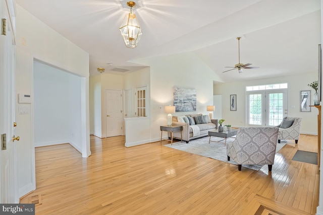 living room with light wood-style flooring, a ceiling fan, baseboards, a chandelier, and high vaulted ceiling
