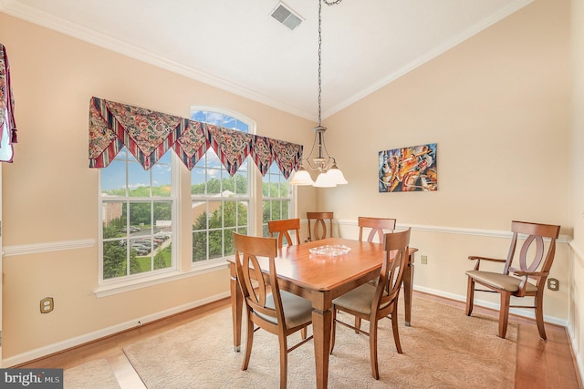 dining room featuring light wood-style floors, baseboards, crown molding, and vaulted ceiling