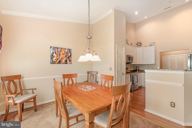 dining room featuring a high ceiling, light wood finished floors, crown molding, and baseboards